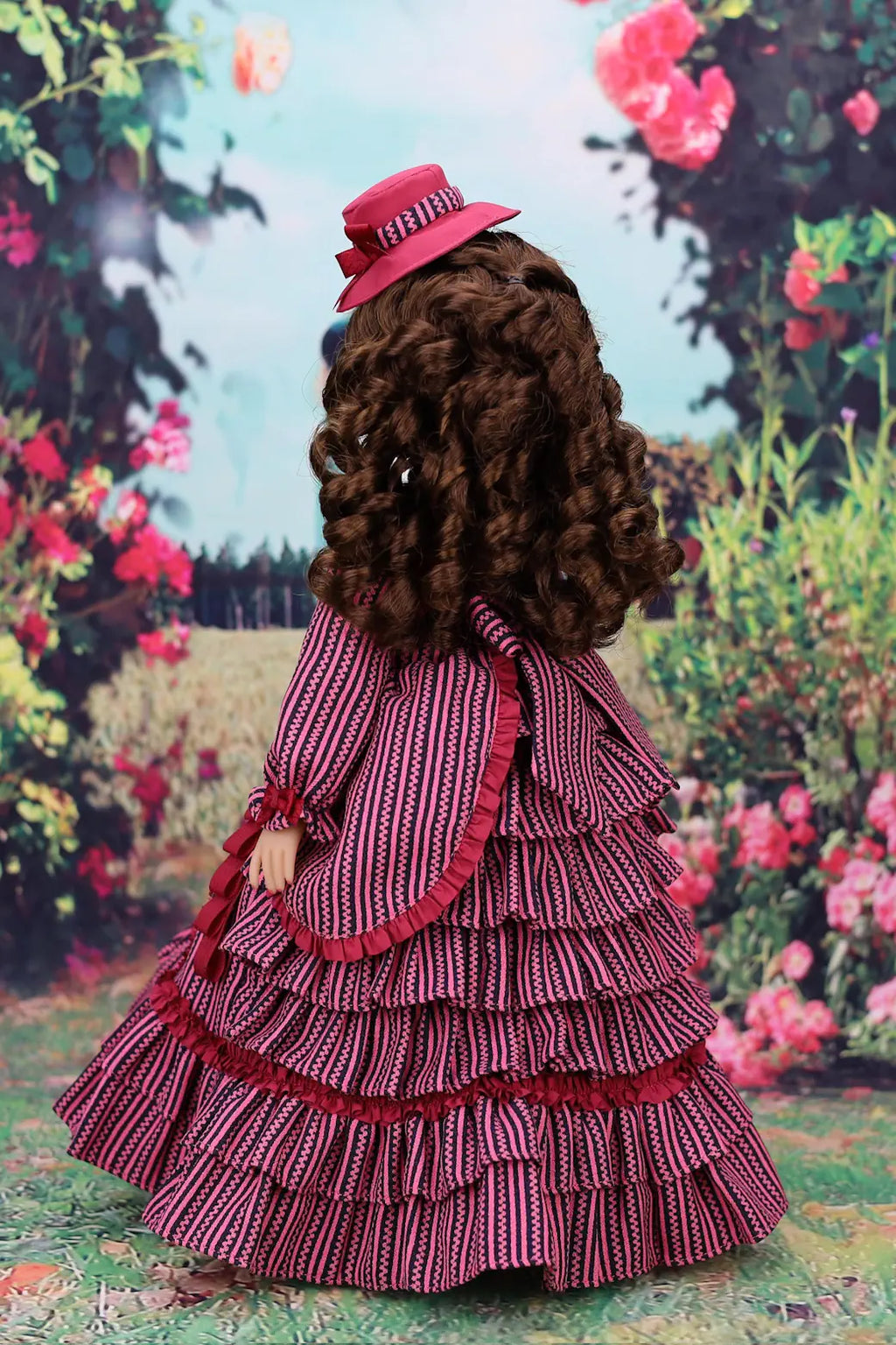 Doll in a vintage-style dress with a magenta hat against a floral garden backdrop