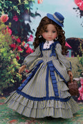 Doll in a vintage dress with blue accents standing in a garden setting