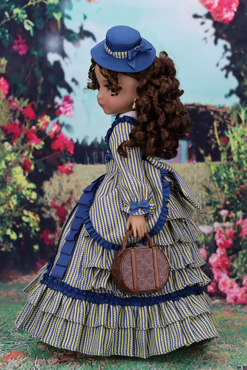 Doll in a vintage outfit with a blue hat and dress, holding a bag, against a floral background.