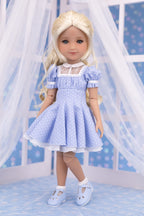 Doll wearing a blue dress with white polka dots against a white background