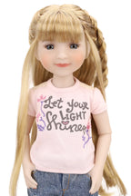 Doll with long blonde hair wearing a pink shirt with text and denim pants on a white background