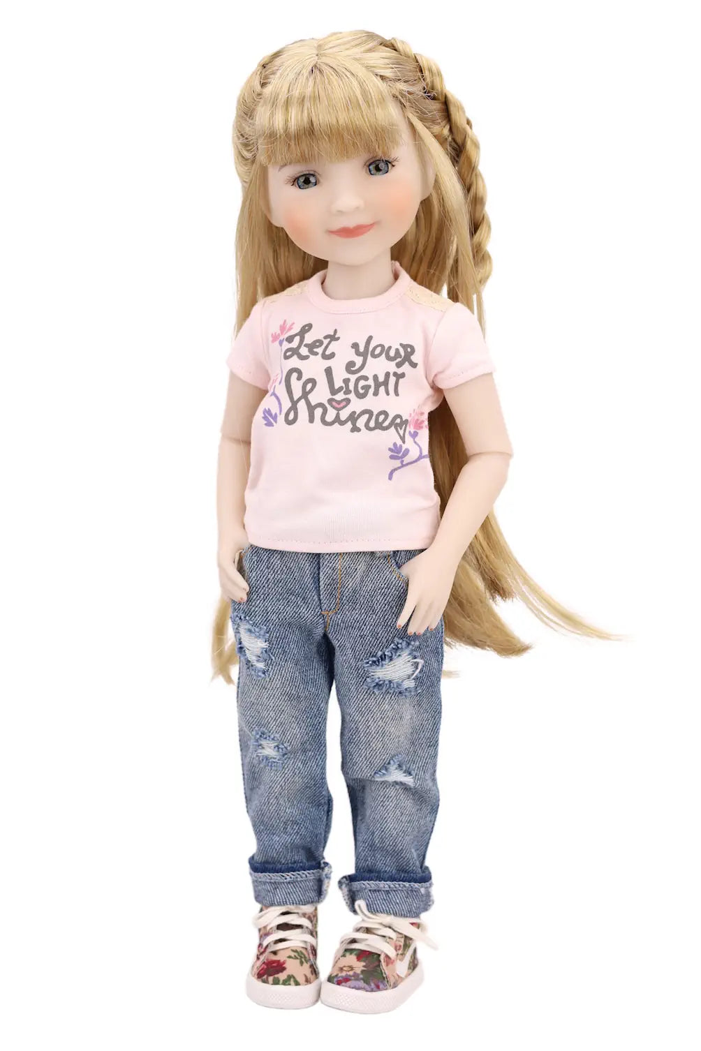 Doll wearing a pink shirt with text and blue jeans on a white background