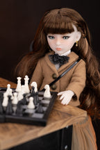 Doll in a brown coat playing chess on a wooden table