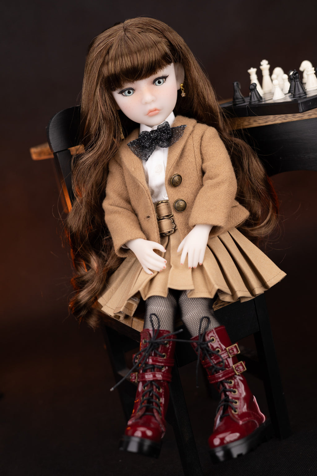 Doll in a stylish outfit with a coat, bow tie, and red boots on a dark background
