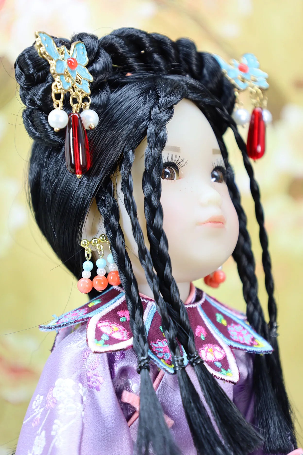 Close-up of a doll with traditional hairstyle and accessories against a blurred background