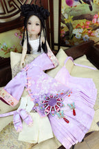 Traditional doll in a purple outfit with decorative elements on a floral background