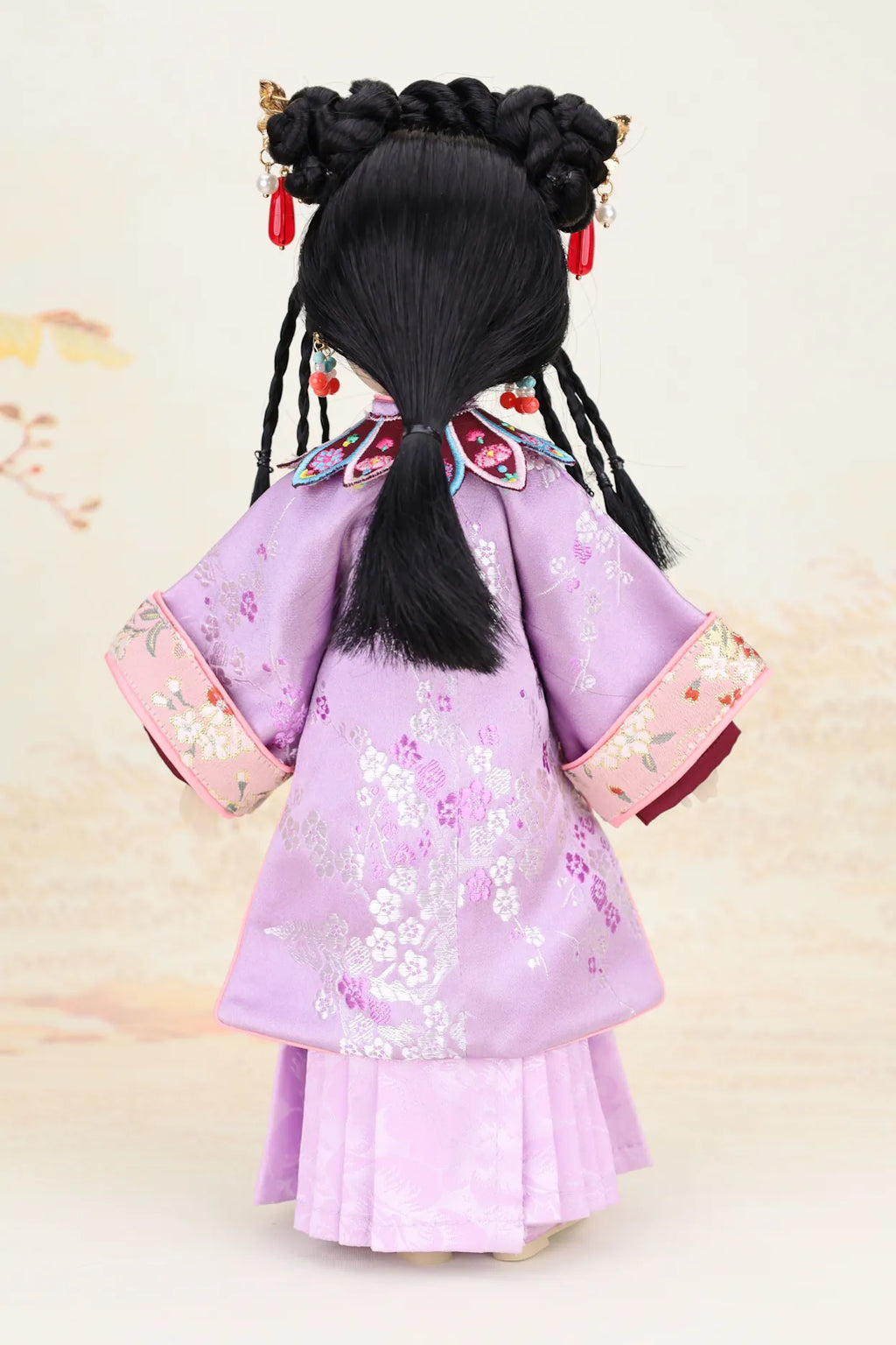 Doll in a traditional outfit with a light purple kimono and black hair styled in buns.