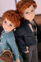 Two dolls with red hair, one in a blue coat and the other in a dark outfit, standing close together.