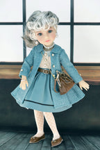 Doll wearing a dark turquoise coat and skirt with a brown bag against a neutral background