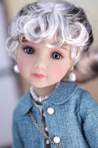 Close-up of a doll with white hair and blue eyes wearing a dark turquoise coat and pearl necklace.
