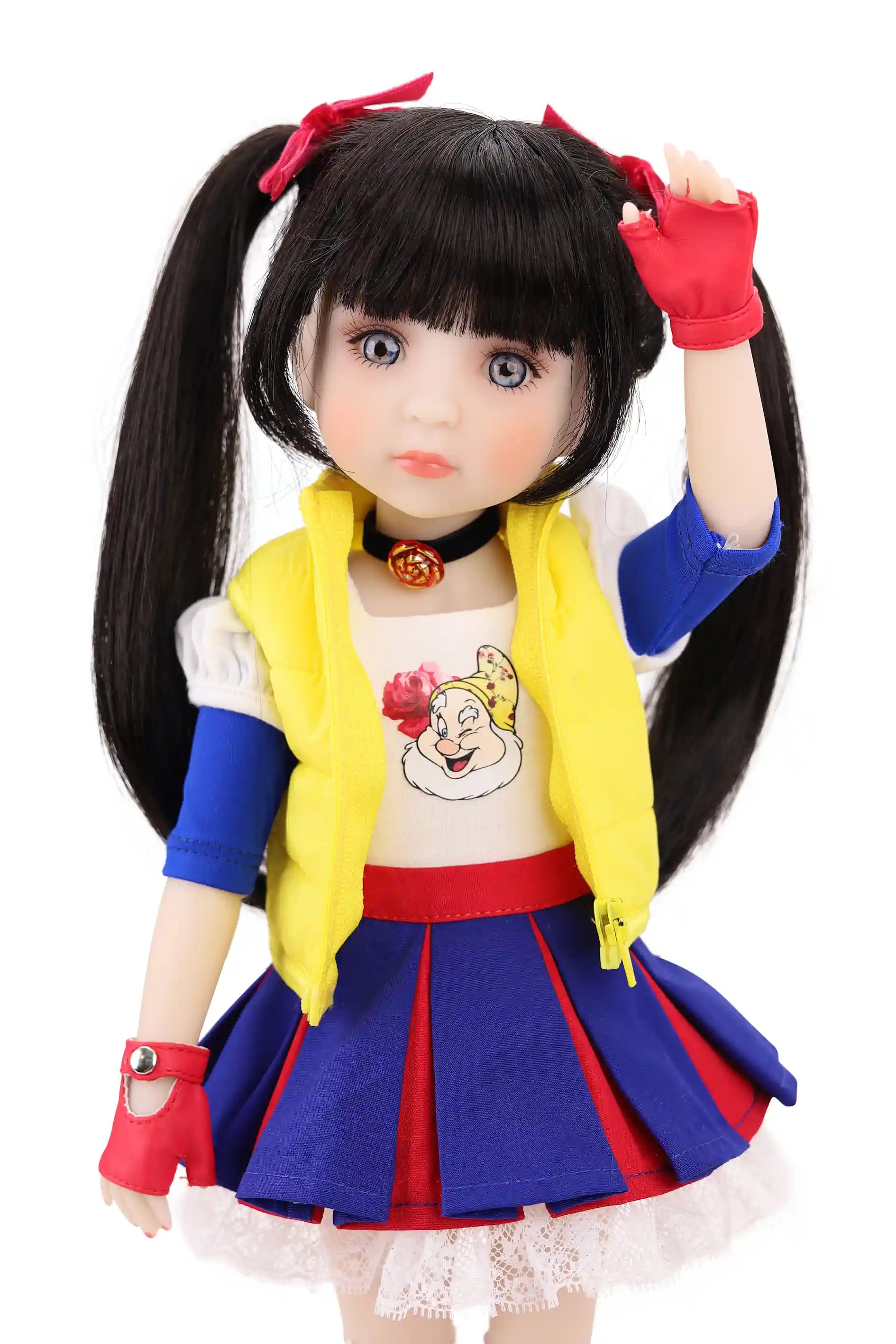 Doll with long black hair styled in pigtails, wearing a colorful outfit with a yellow vest, blue skirt, and red shoes on a white background.