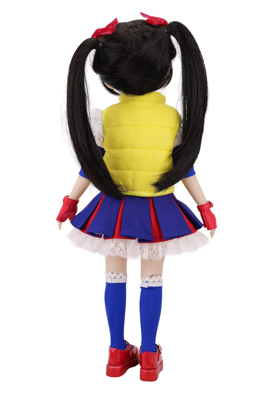 Back view of a doll in a colorful outfit with a yellow vest, blue skirt, and red shoes on a white background.