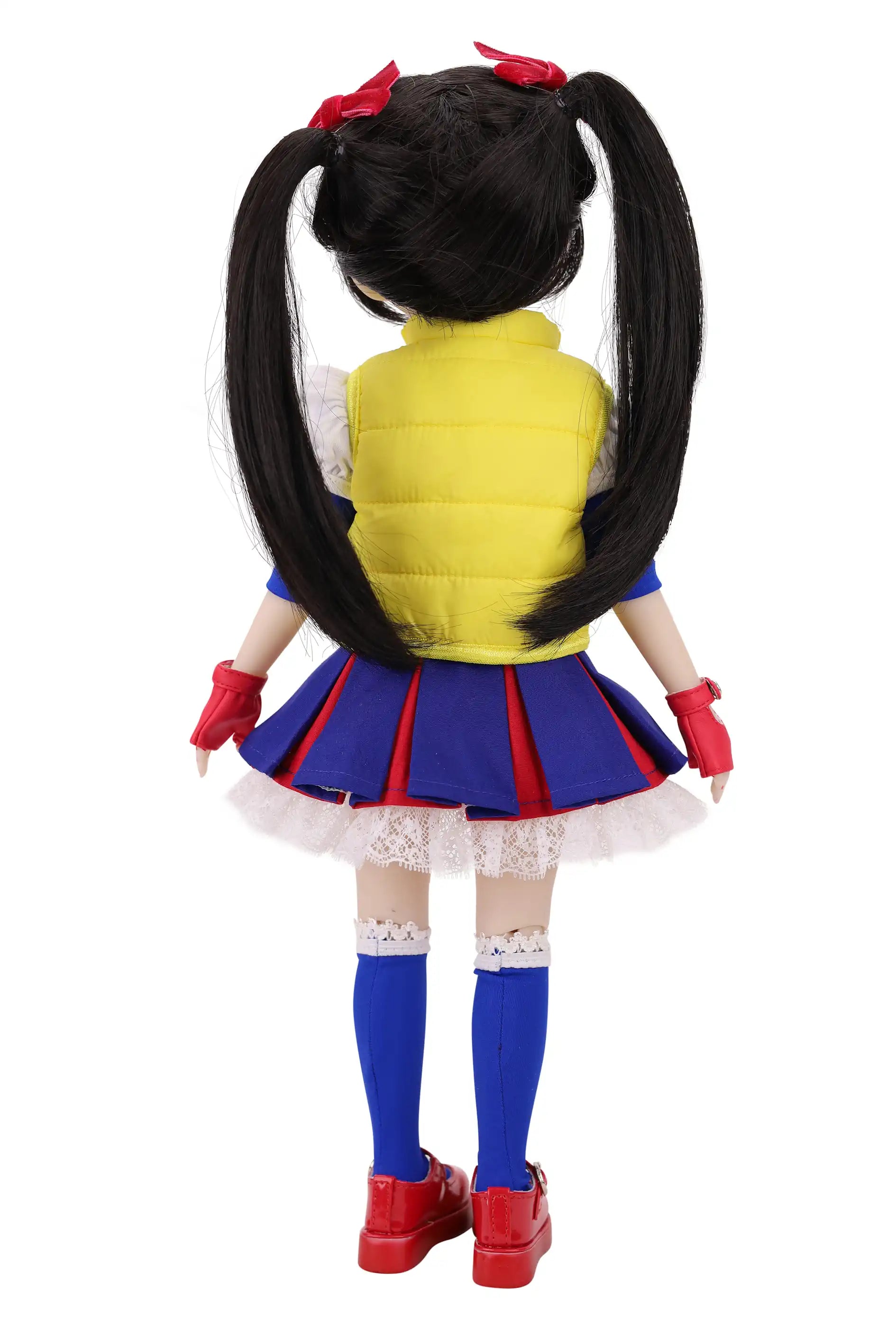 Back view of a doll in a colorful outfit with a yellow vest, blue skirt, and red shoes on a white background.