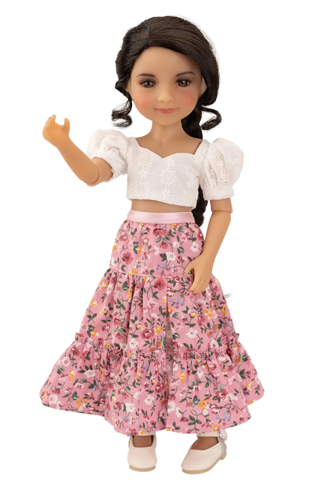 Doll wearing a white top and pink floral skirt on a white background