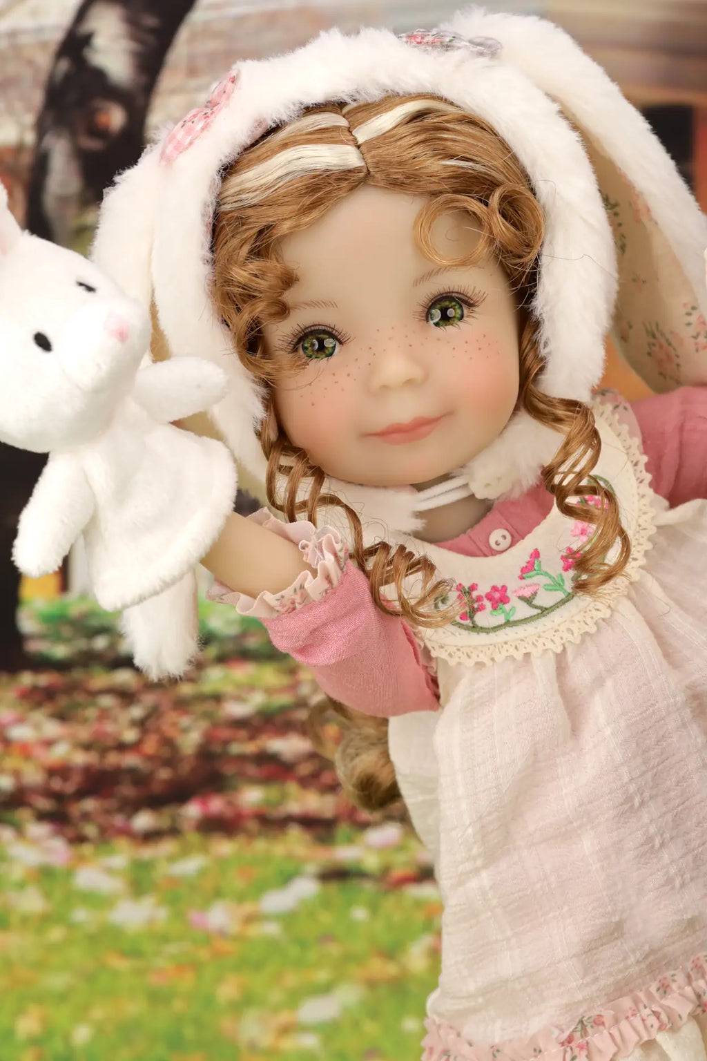 Doll in a white outfit with bunny ears and a pink dress, holding a white rabbit toy.