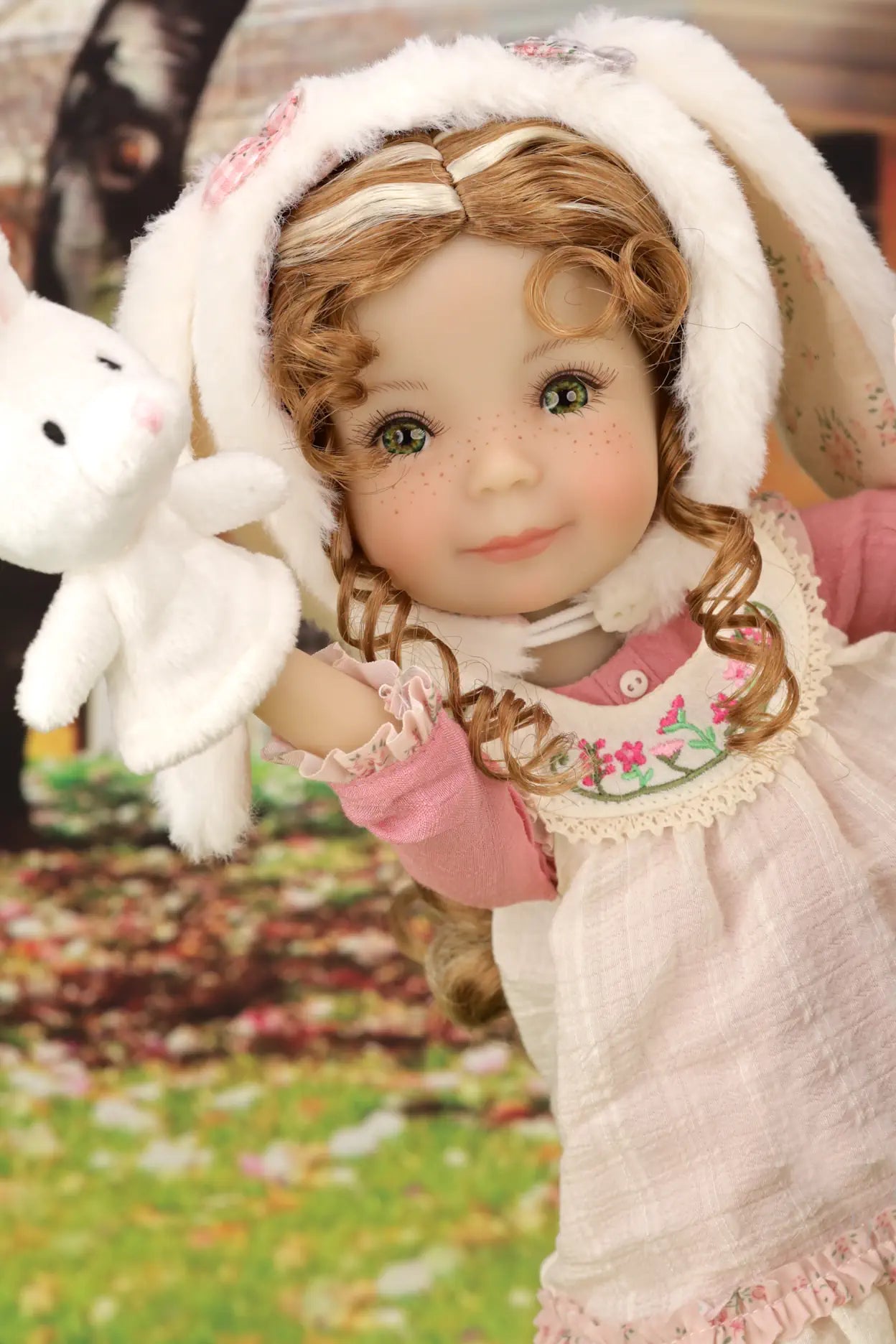 Doll in a white outfit with bunny ears and a pink dress, holding a white rabbit toy.