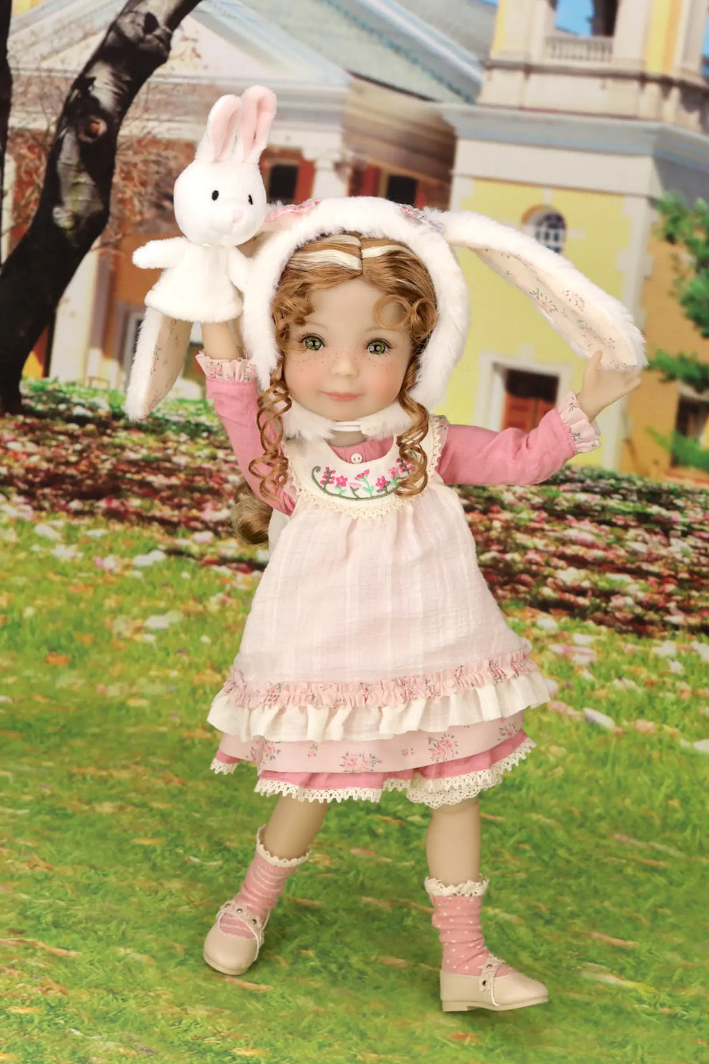 Doll in a pink dress holding a white rabbit toy outdoors.