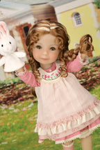 Doll in a pink dress holding a white rabbit toy with a garden background
