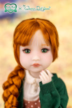 Doll with red hair and green eyes wearing a green outfit against a blurred background