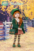 Doll in a green outfit with a bag standing in an outdoor setting with trees and a fence.