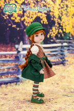 Doll in a green outfit with a polka dot dress standing in a scenic outdoor setting.