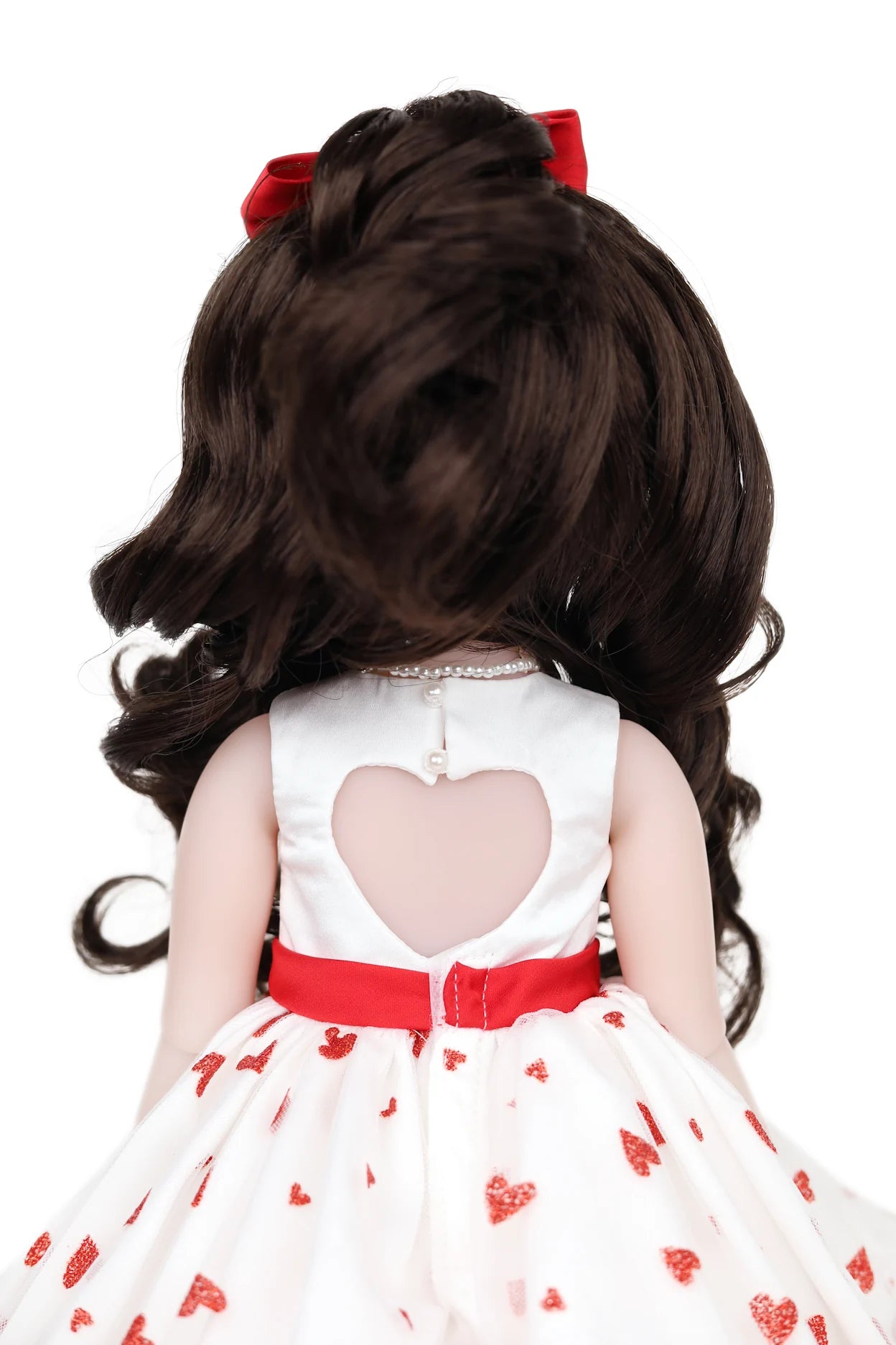 Doll with long dark hair and a white dress with red hearts on a white background