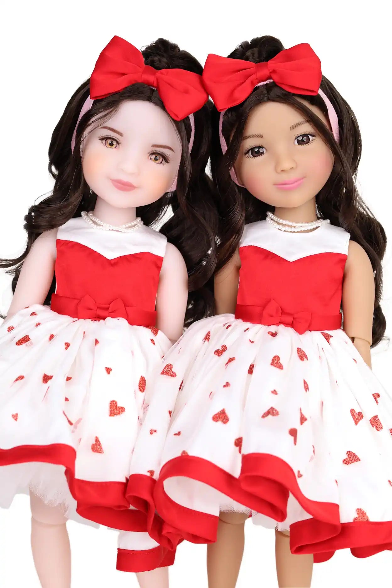 Two dolls wearing red and white dresses with heart patterns, standing side by side.