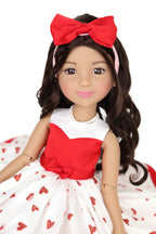 Doll with red bow headband and red and white dress on a white background