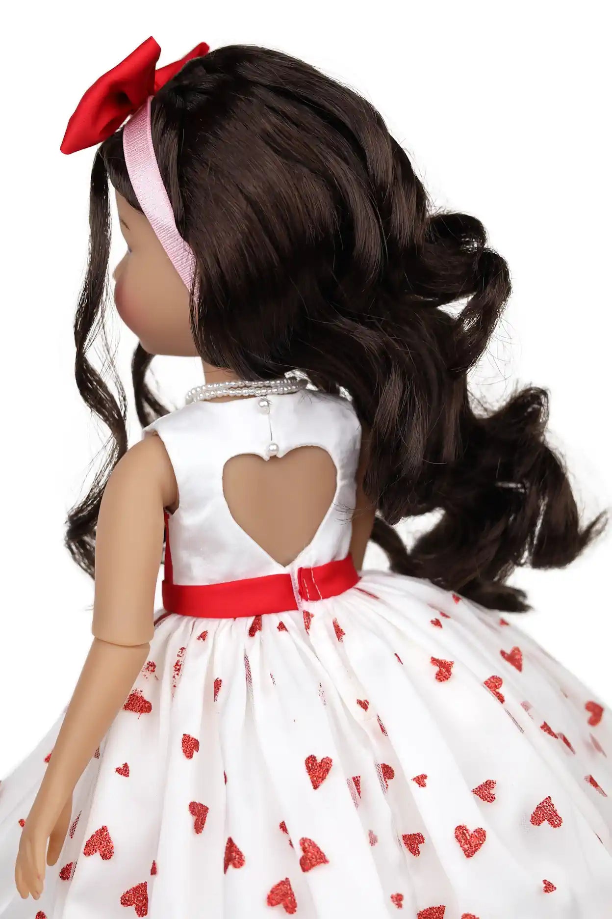Doll wearing a white dress with red hearts and a red belt, on a white background