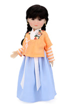 Doll wearing an orange top and light blue skirt on a white background