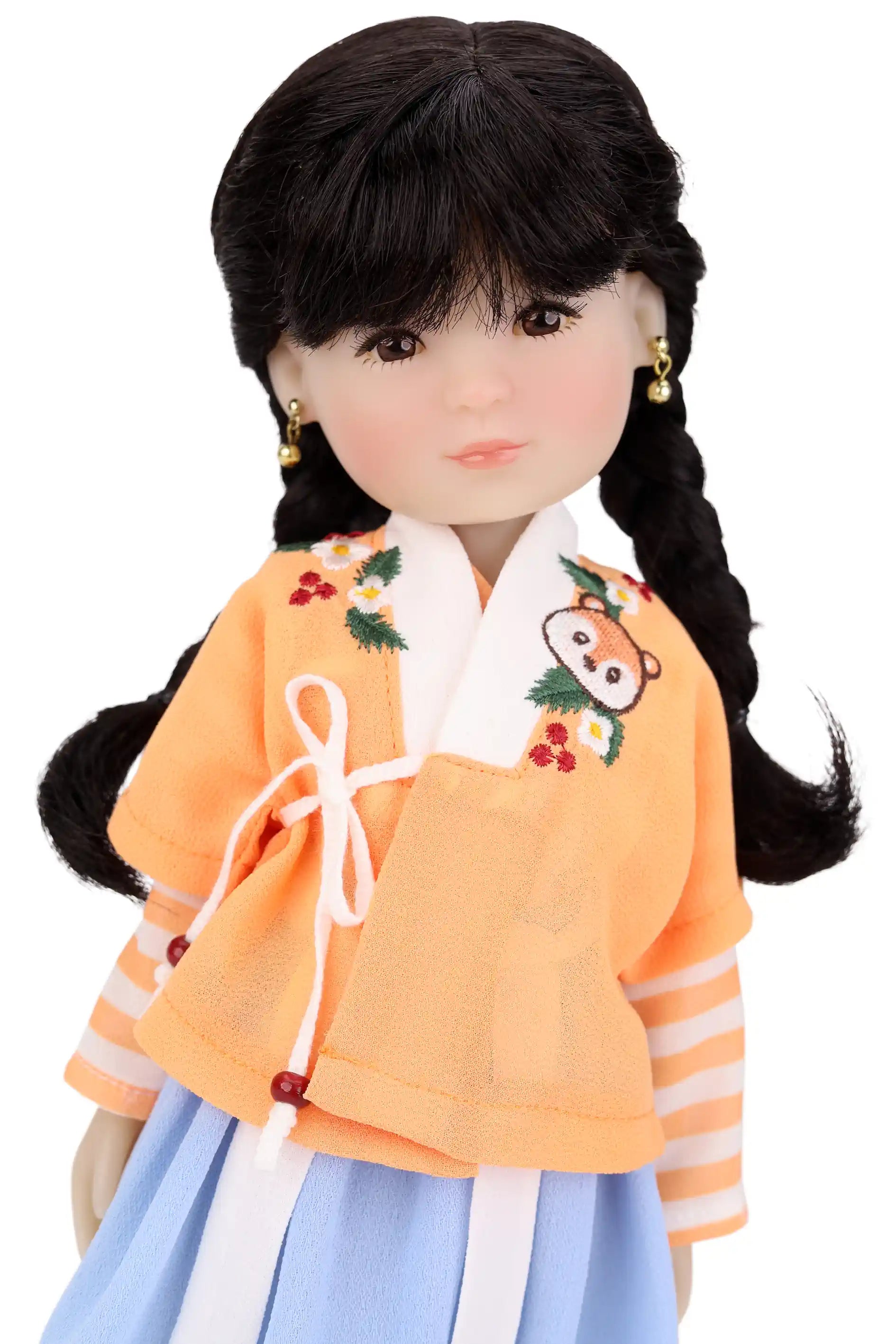 Doll wearing a traditional outfit with an orange top and blue skirt on a white background