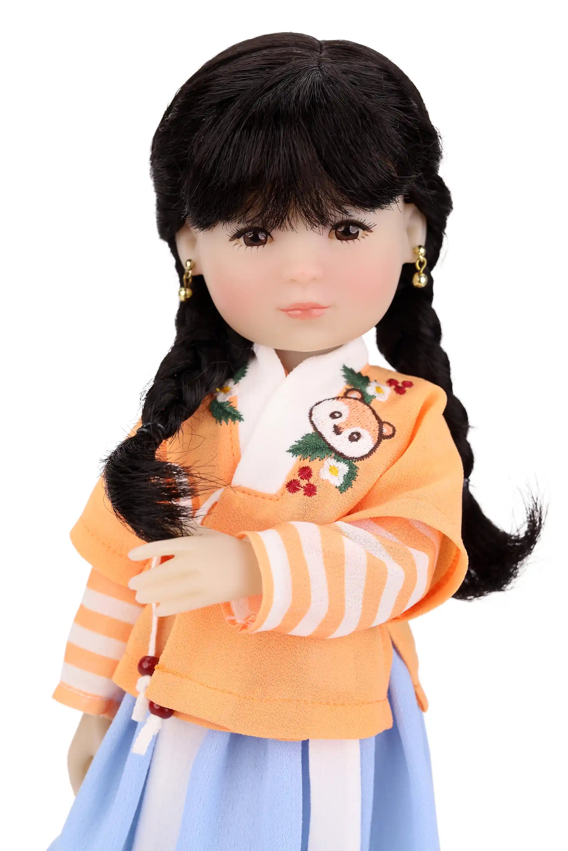 Doll wearing a traditional outfit with an orange top and blue skirt on a white background