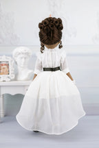 Esther in a white dress with a black belt against a light gray background
