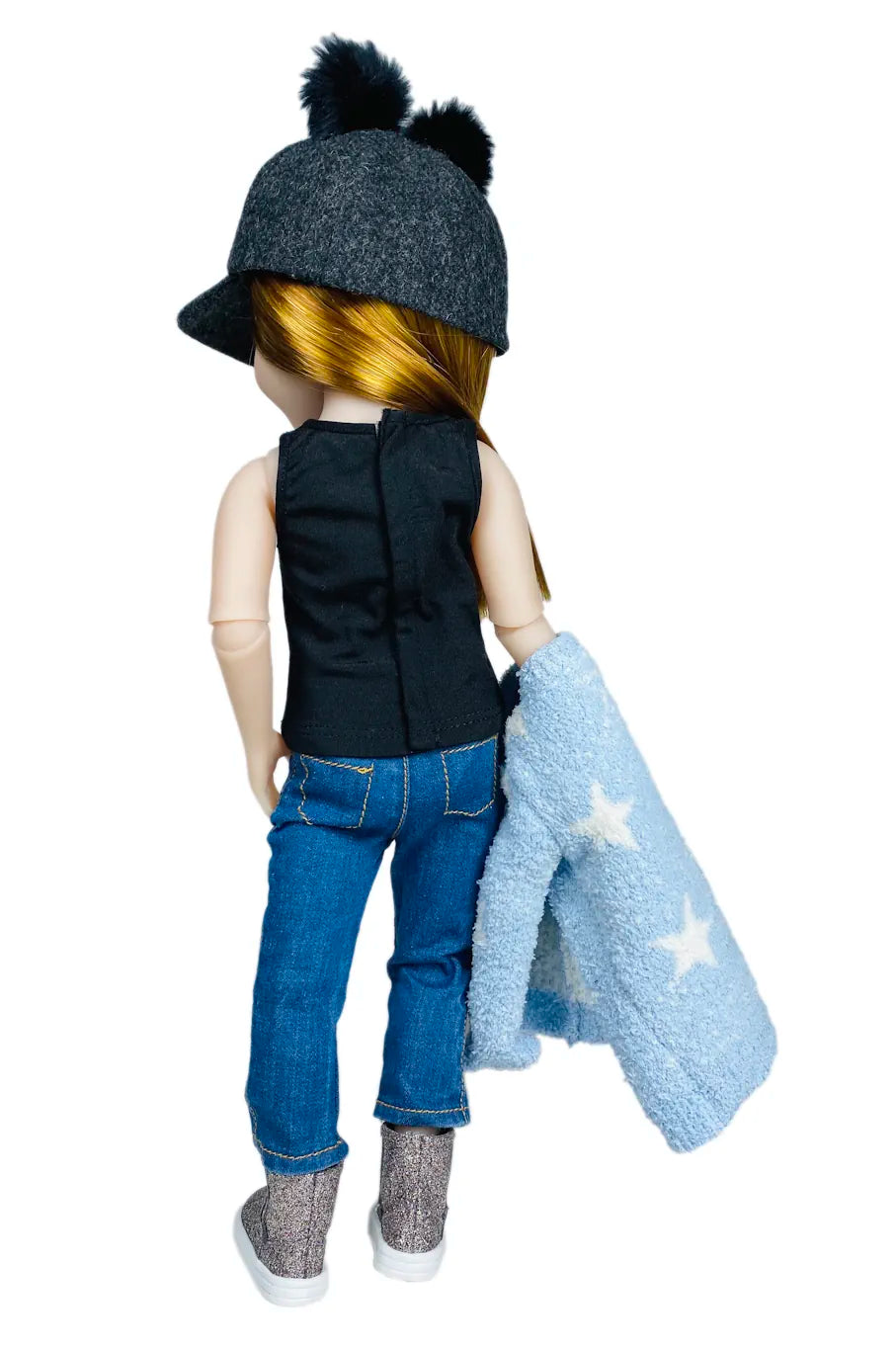 Stella wearing a black sleeveless shirt, blue jeans, and a dark hat, holding a blue blanket with white stars on a white background.