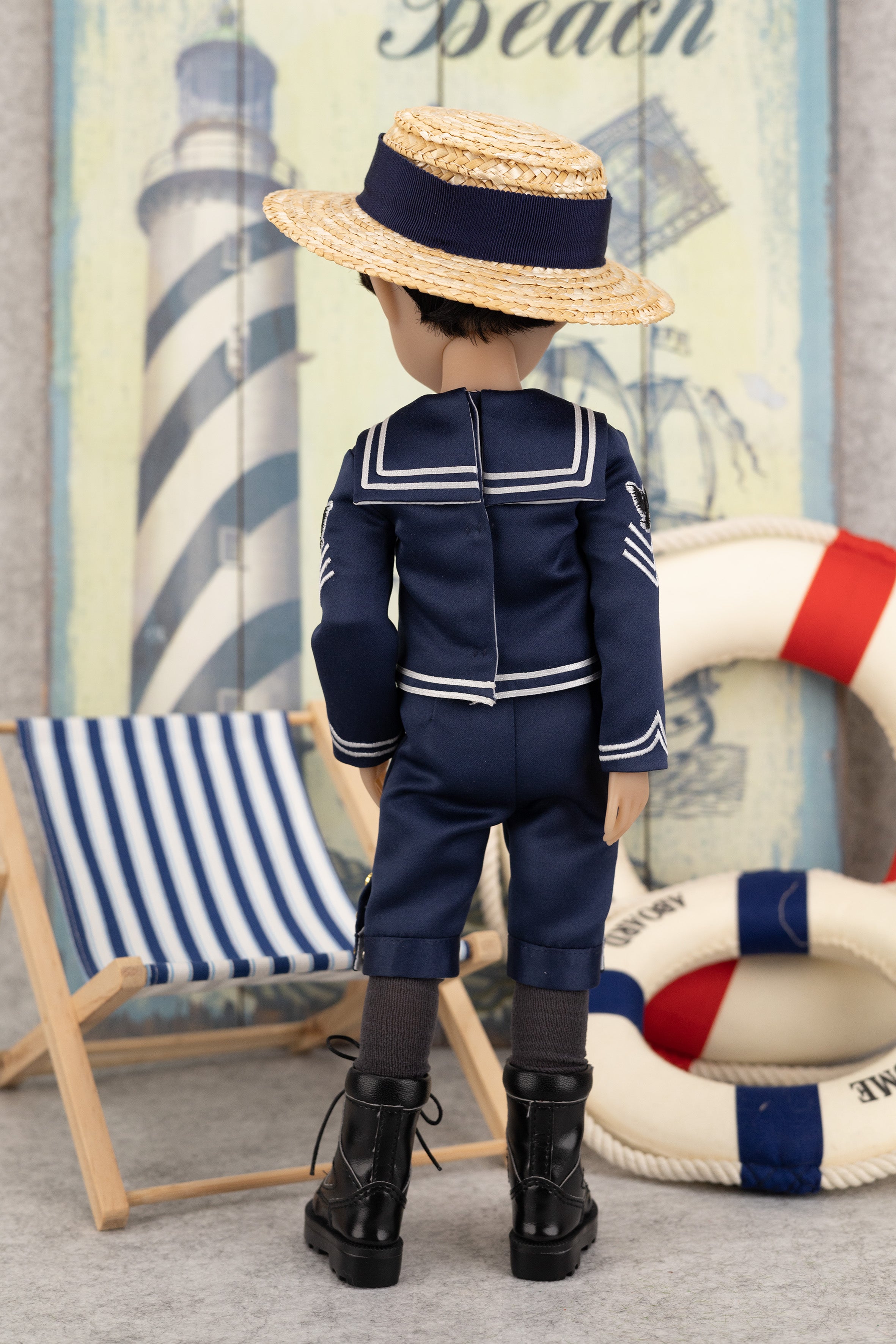 Tyler in a navy blue sailor outfit with a straw hat, standing in front of a lighthouse and life buoy illustration.