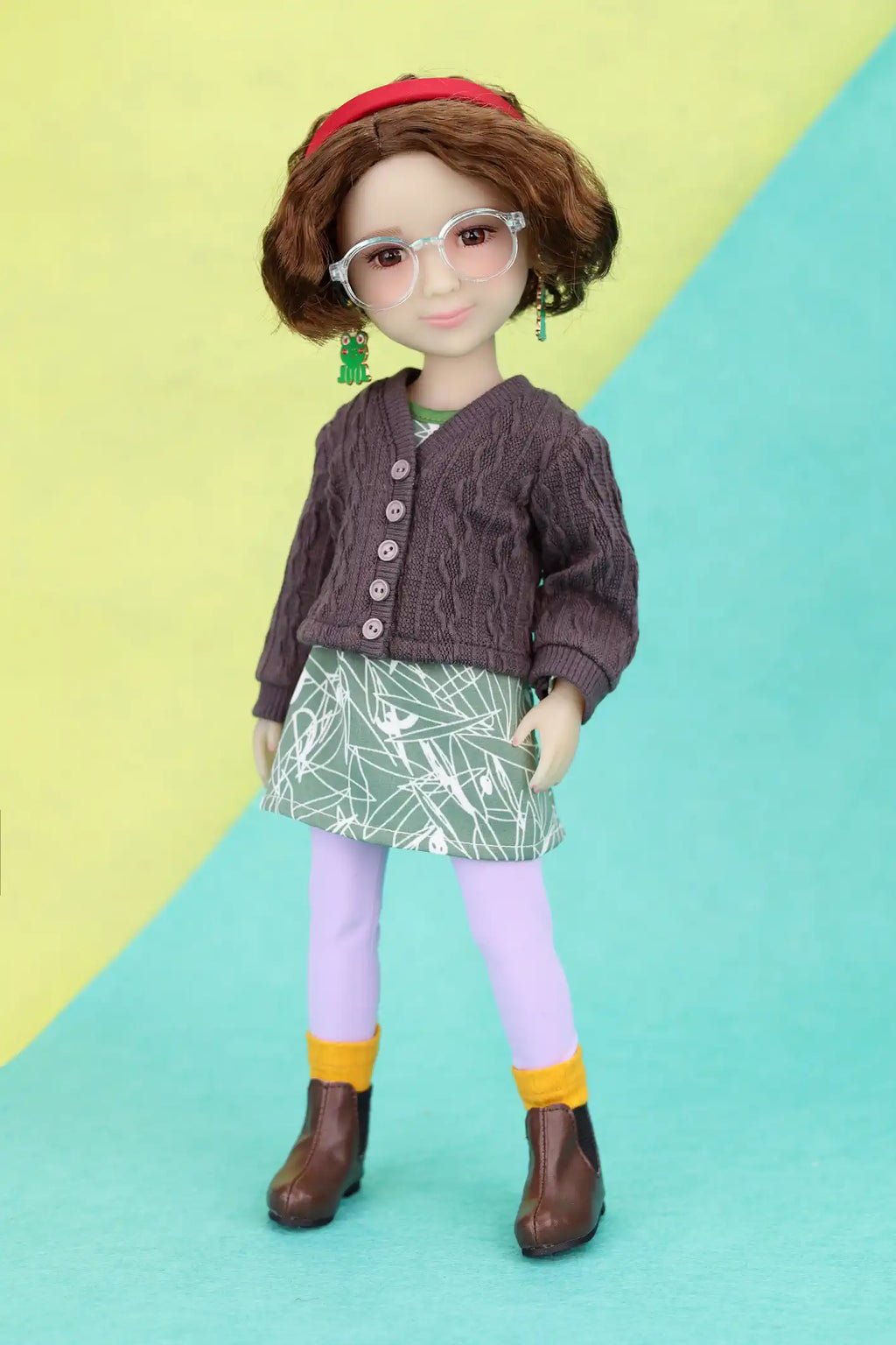 Ava wearing a brown cardigan, green skirt, and purple leggings on a yellow and blue background