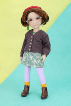 Ava wearing a brown cardigan, green skirt, and purple leggings on a yellow and blue background