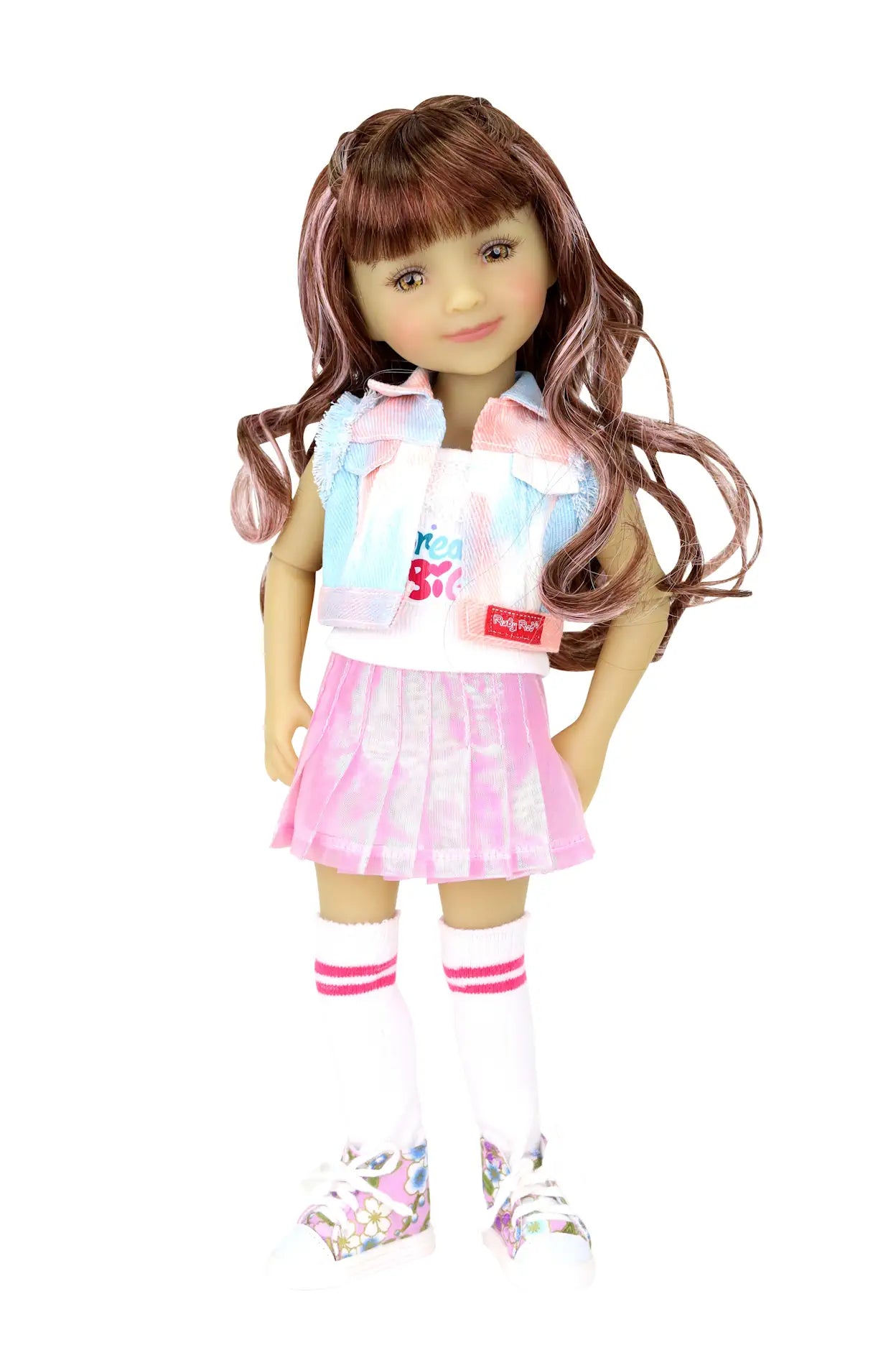 Bella with pink-highlighted wavy hair, wearing white tank, sleeveless jacket, pink skirt, striped socks, and floral sneakers, white background.