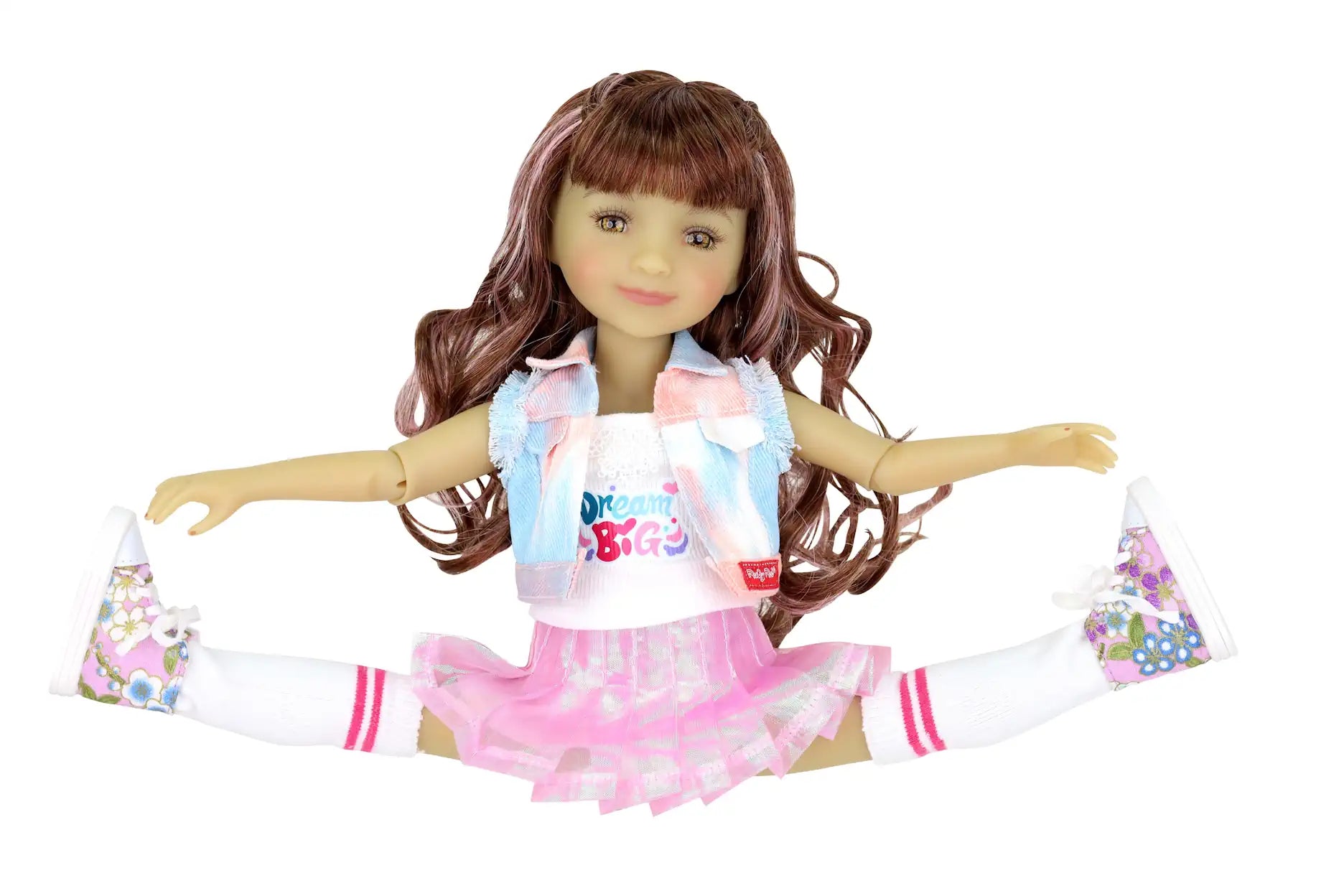 Bella with long wavy brown hair, doing a split in "Dream Big" shirt, plaid vest, pink skirt, knee-high socks with pink stripes, and floral sneakers.