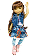 Bella wearing a denim jacket, colorful skirt, and pink shoes on a white background