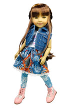 Bella wearing a denim jacket, patterned skirt, and pink shoes on a white background
