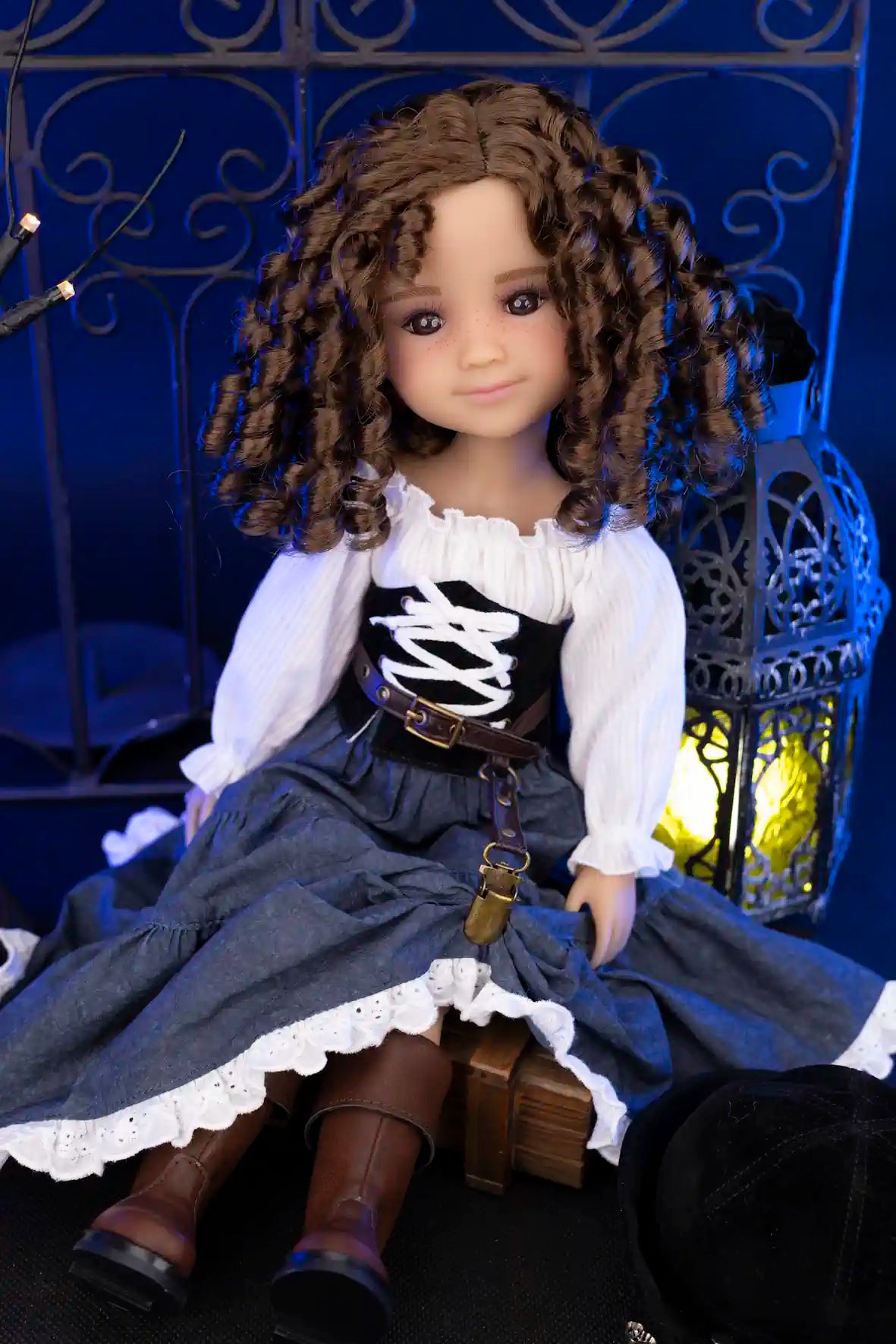 Clark with curly hair wearing a white blouse and blue skirt in front of a decorative metal gate.