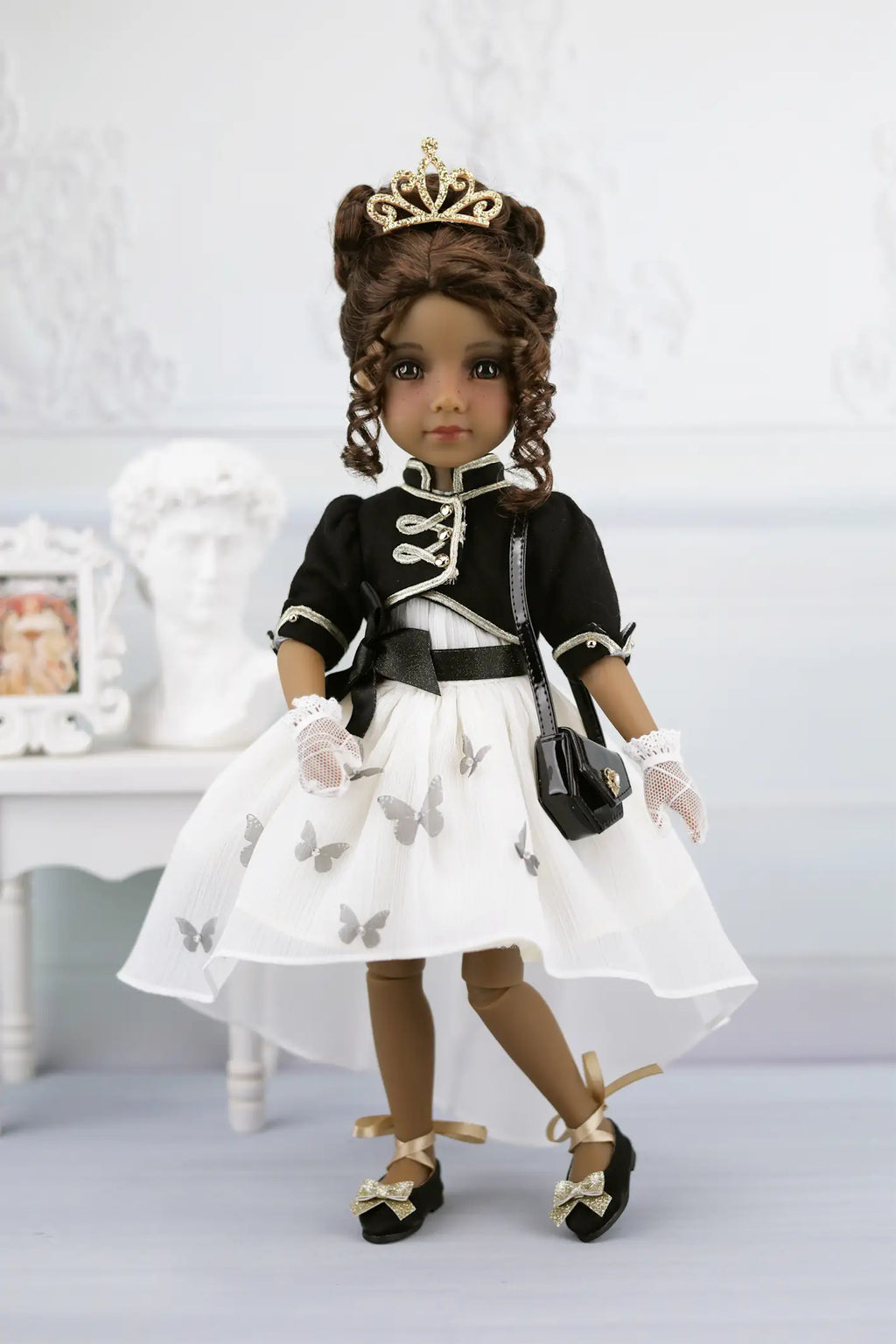 Esther in formal attire with a white dress, black jacket, and tiara on a light background