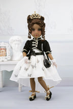 Esther in formal attire with a white dress, black jacket, and tiara on a light background