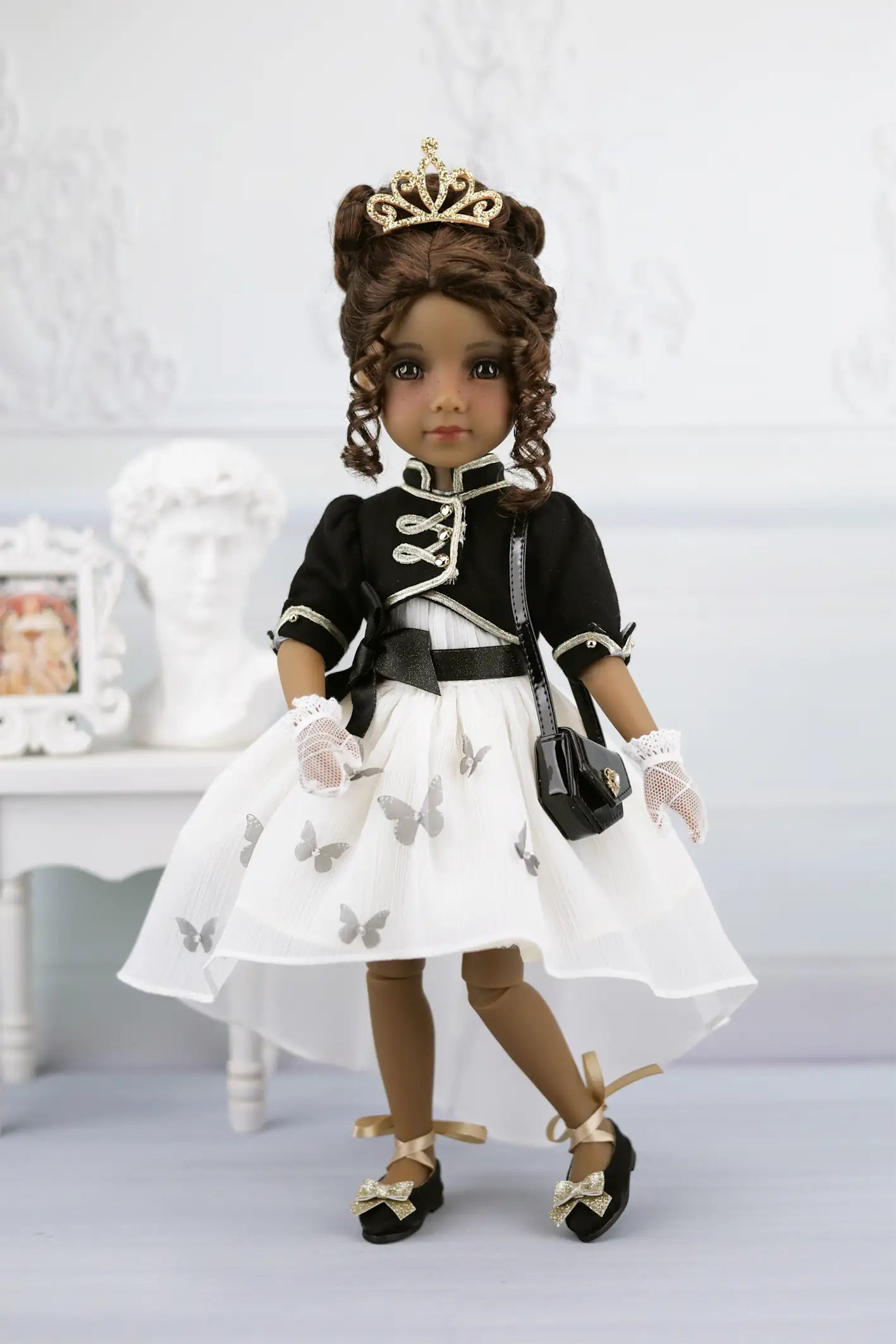 Esther in formal attire with a white dress, black jacket, and tiara on a light background