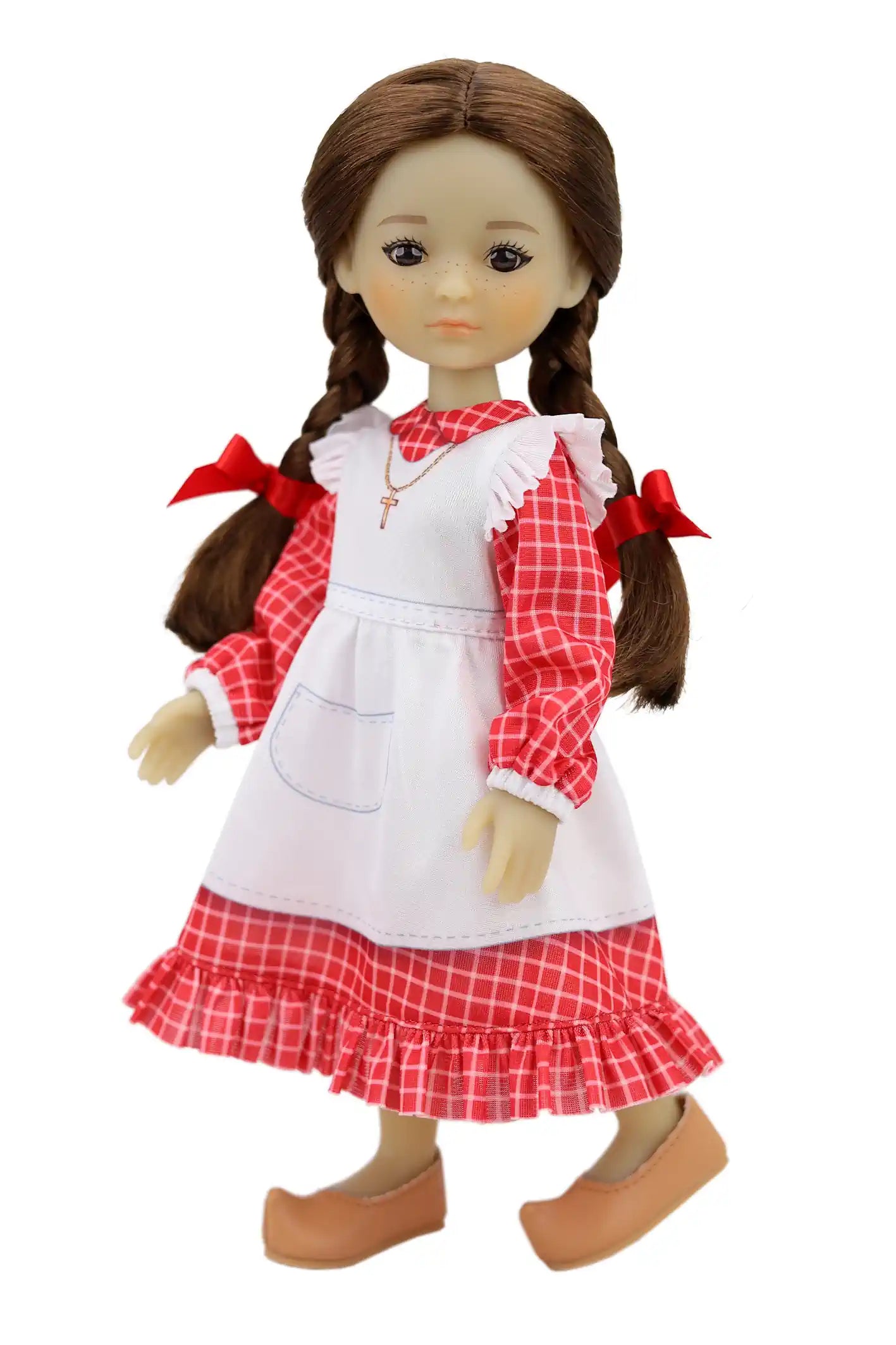 Jeannette, adorned with brown braids and red bows, has a checkered dress, a tied white apron, a gold cross necklace, and slip-on brown shoes.