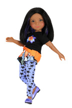 Kelsey wearing a black shirt with colorful design, orange and blue skirt, and star-patterned leggings on a white background.