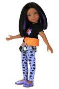 Kelsey wearing a black shirt with a colorful design, orange belt, and blue pants with black patterns on a white background.