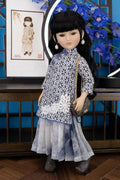 Kiki Doll in a traditional outfit with a blue floral background