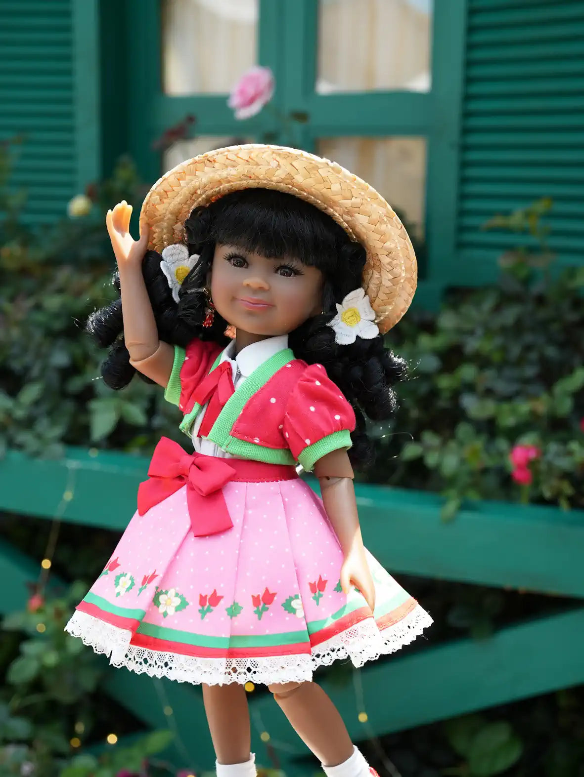 Kyra in traditional outfit with straw hat and floral decorations, standing in front of a green wooden door.